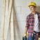 Young carpenter is holding electric saw and looking away